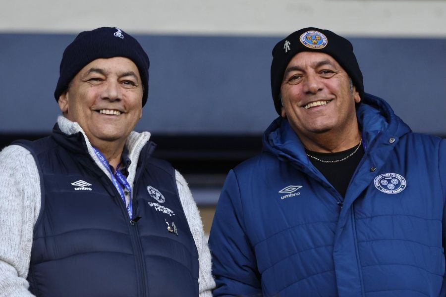 Twin brothers Dave and Pete smiling at a football match.