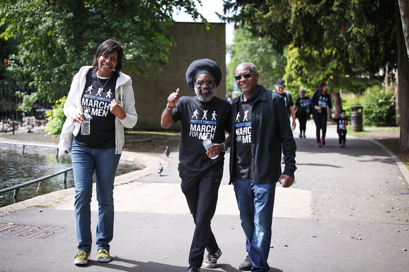 Two men and a woman taking part in our 'March for Men' event, walking along a path and smiling