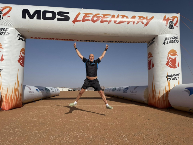 A man jumping and smiling at a marathon start line.